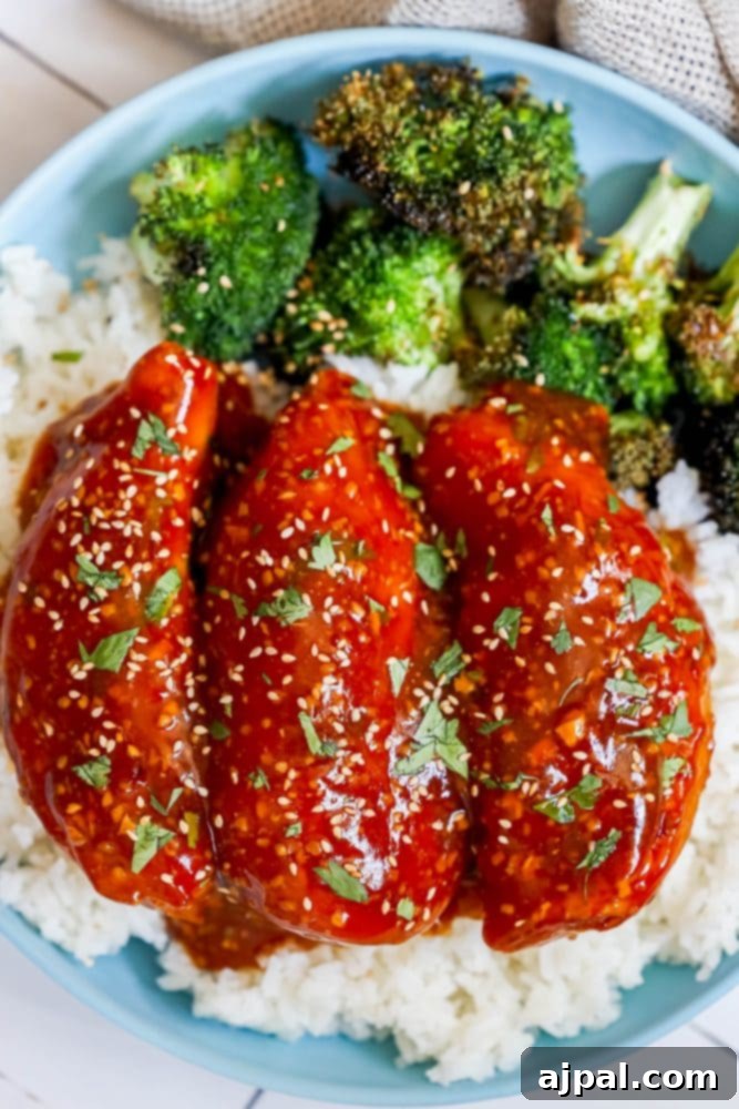 Sticky Honey Garlic Slow Cooker Chicken Breasts 3 A delicious serving of honey garlic chicken on a plate, garnished with fresh herbs and accompanied by vibrant broccoli and fluffy rice.