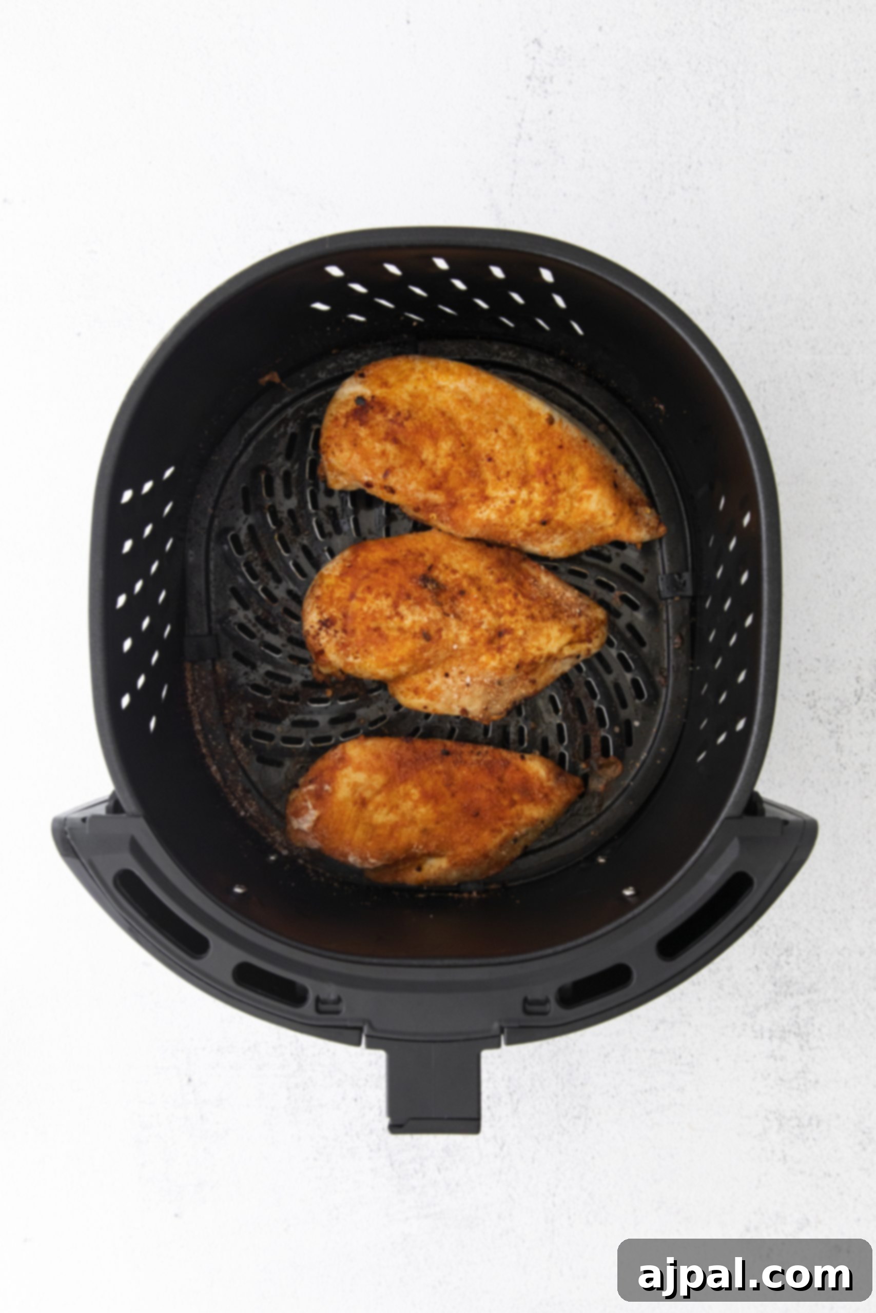 Tender Air Fryer BBQ Chicken Breasts 8 Two chicken breasts in an air fryer on a white background.