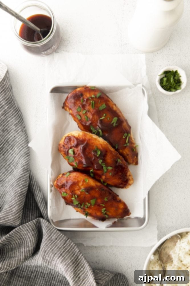 Tender Air Fryer BBQ Chicken Breasts 4 Air fryer bbq chicken breasts on a tray with rice and sauce.