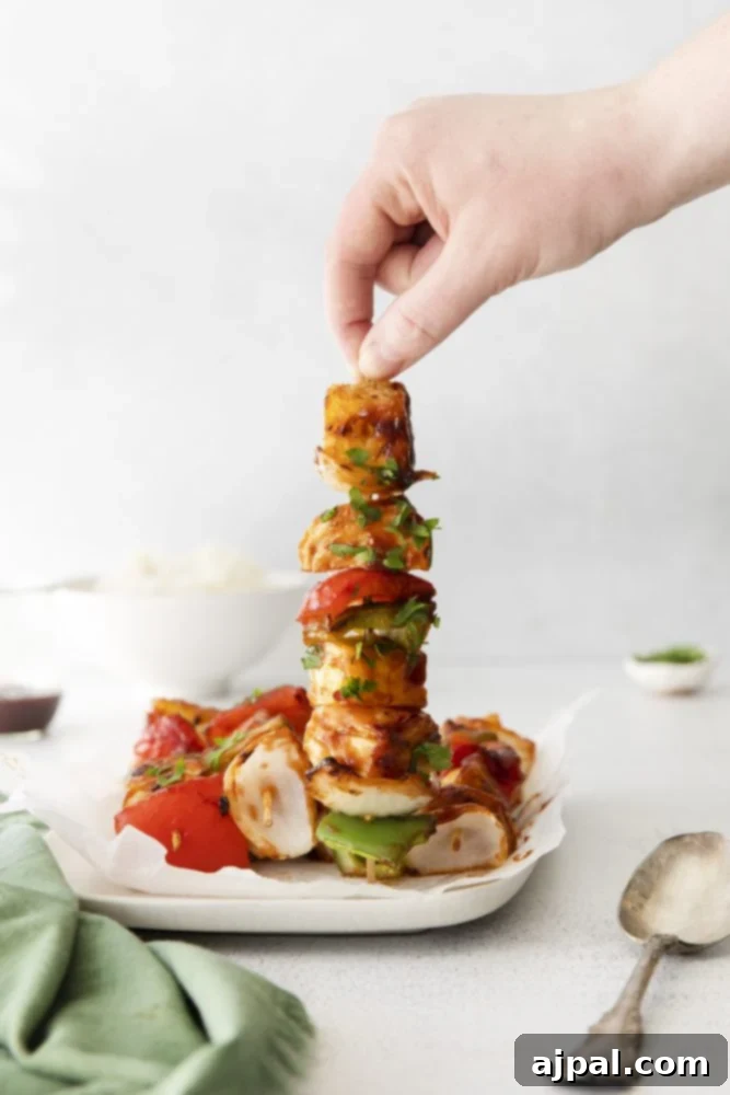 Close-up of succulent Grilled Huli Huli Chicken Kabobs on a white plate, showcasing the caramelized chicken, vibrant pineapple, and colorful bell peppers.