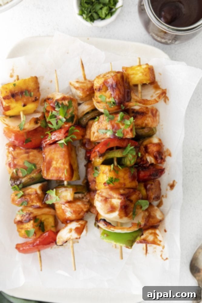 A perfectly grilled Huli Huli chicken kabob, featuring caramelized chicken, golden pineapple, and tender bell peppers, arranged appealingly on a white plate, ready to be enjoyed.