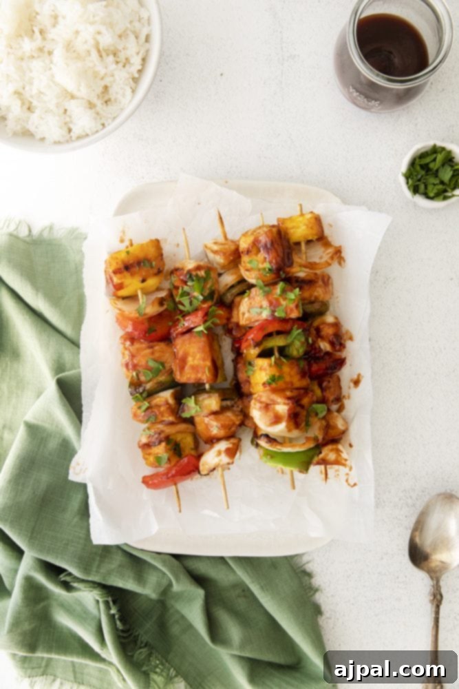 A vibrant plate featuring grilled huli huli chicken skewers alongside fluffy white rice, garnished with fresh green onions for a delicious Hawaiian-inspired meal.