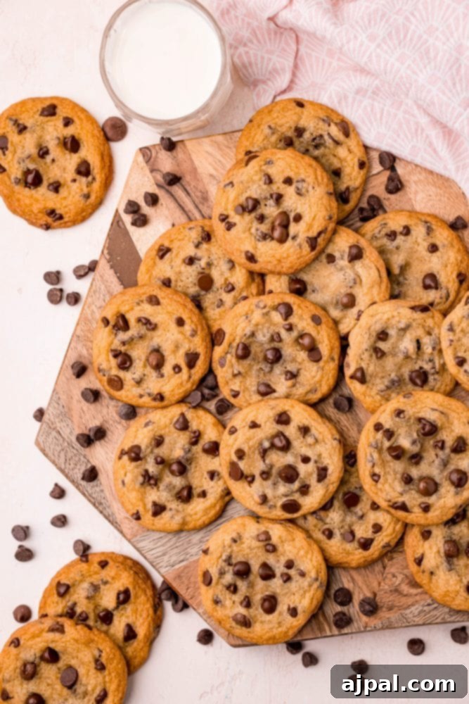 Ultimate Chewy Chocolate Chip Cookies 9 A rustic wooden cutting board laden with warm, golden-brown classic chocolate chip cookies, freshly baked and ready for tasting.