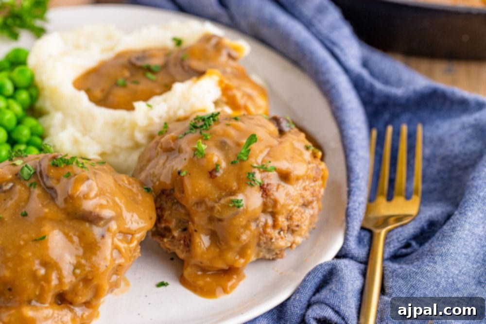 Rich Salisbury Steaks with Velvety Mushroom Gravy 2 Classic Salisbury steak with rich mushroom gravy, served alongside creamy mashed potatoes and vibrant green peas.