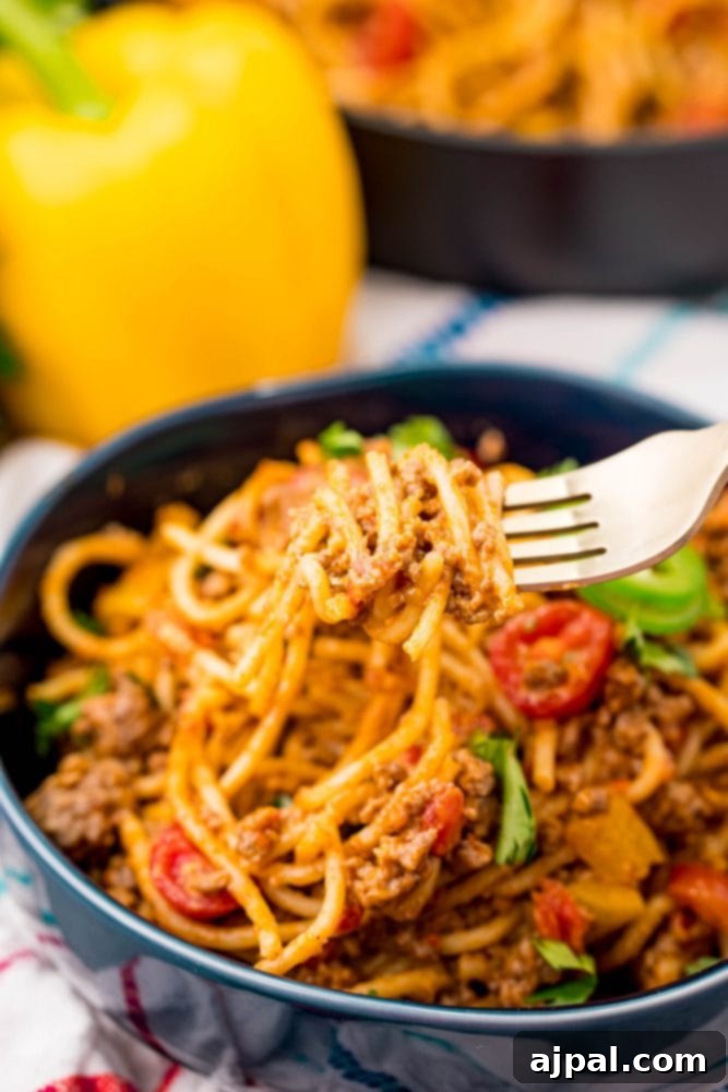 Quick and Delicious Taco Spaghetti 11 A vibrant blue bowl holds spaghetti and meatballs, with a fork poised for a bite, next to a generous serving of cheesy taco spaghetti, highlighting a fusion meal.