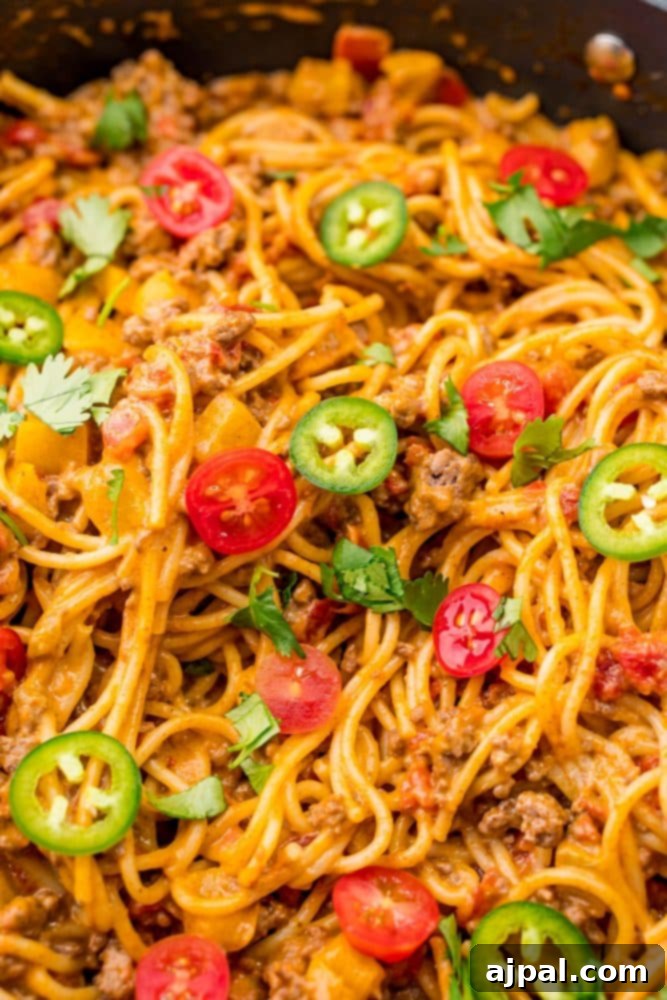 Quick and Delicious Taco Spaghetti 3 A close-up shot of cheesy taco spaghetti sizzling in a skillet, showcasing the rich colors and textures of the ingredients.