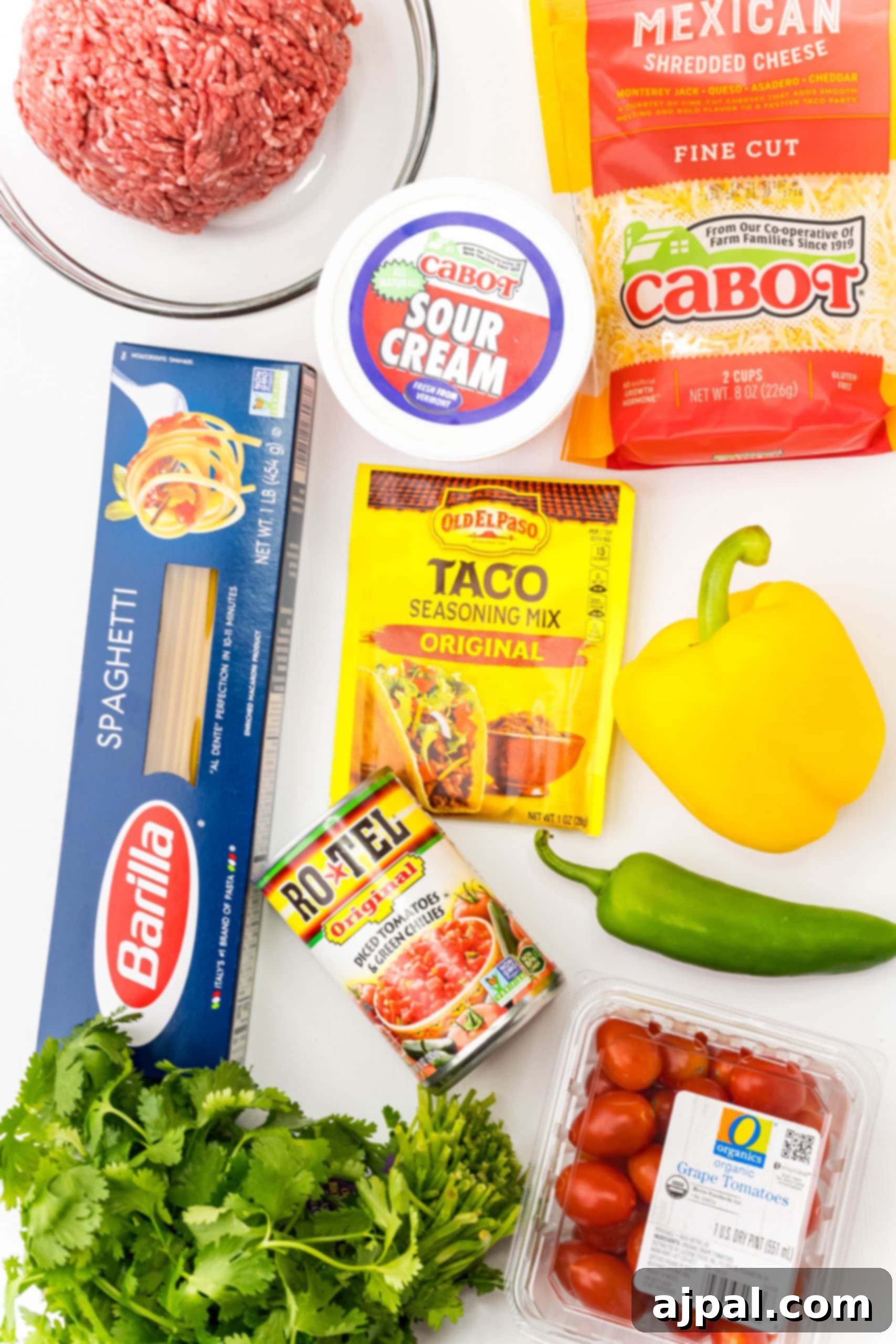 Quick and Delicious Taco Spaghetti 4 All the fresh ingredients for a one-pot taco spaghetti recipe are meticulously arranged on a clean white surface, showcasing their vibrant colors and readiness for cooking.