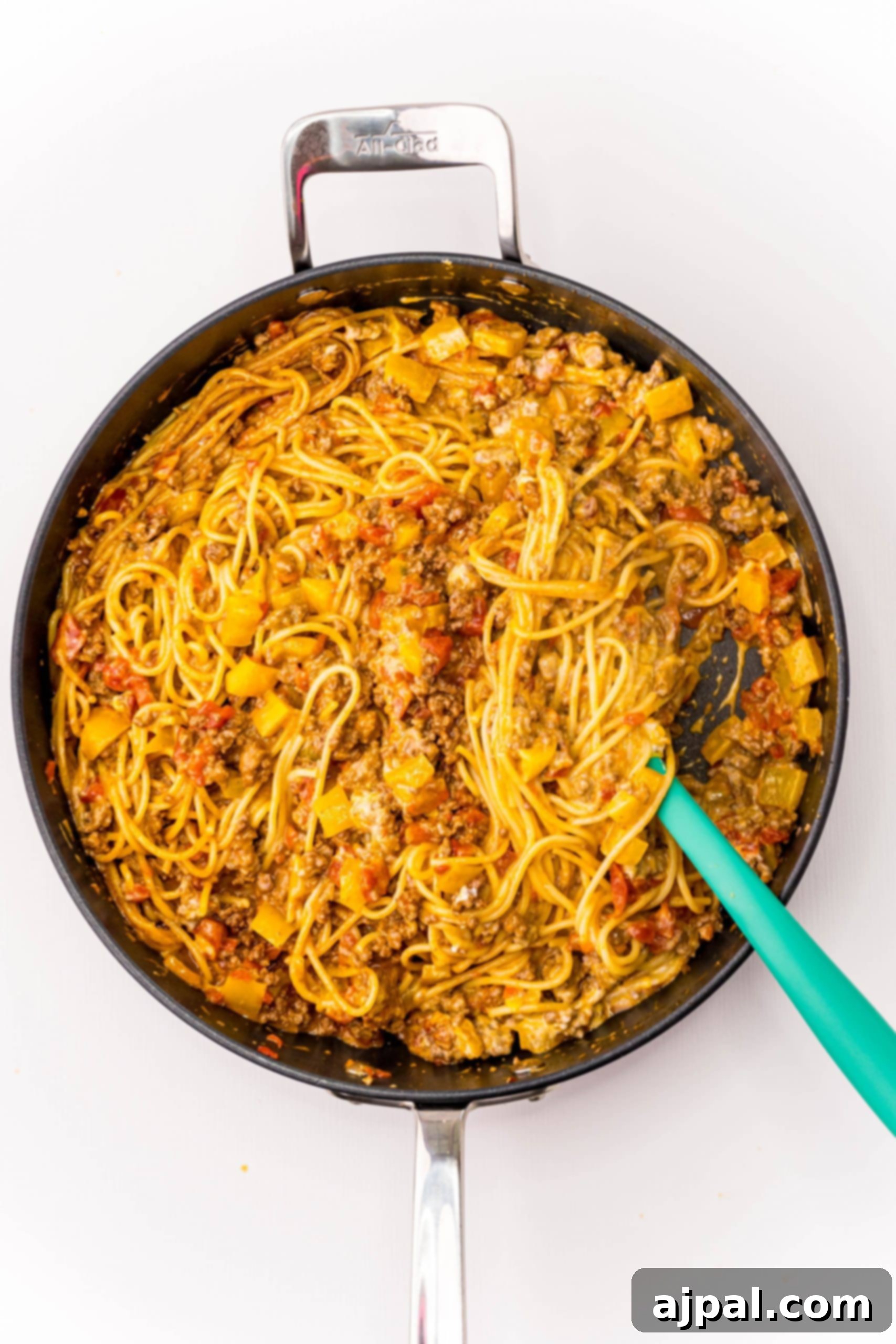 Quick and Delicious Taco Spaghetti 8 A green spatula rests in a pan of spaghetti and meatballs, illustrating the ease of one-pot cooking for this hearty meal.