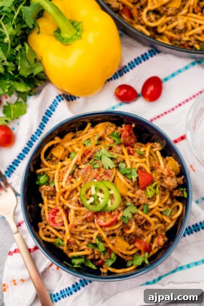 Quick and Delicious Taco Spaghetti 9 A vibrant blue bowl filled with hearty one-pot taco spaghetti, featuring cheesy meatballs, fresh tomatoes, and colorful peppers, inviting a delicious meal.
