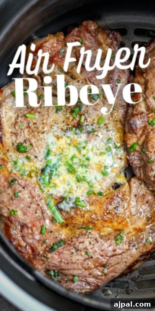 Air Fryer Ribeye Perfection 12 Two perfectly cooked ribeye steaks nestled in an air fryer basket, garnished with melted butter and fresh chives, ready to be served.