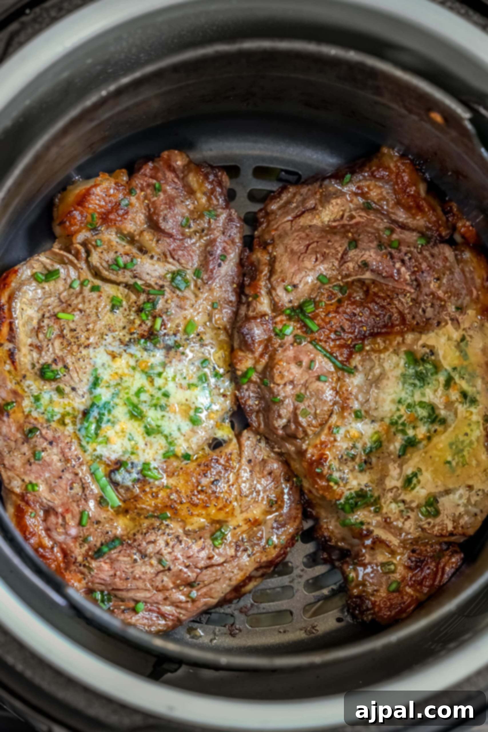 Air Fryer Ribeye Perfection 7 A perfectly cooked air-fried ribeye steak, resting on a plate with a dollop of compound butter melting over its surface.
