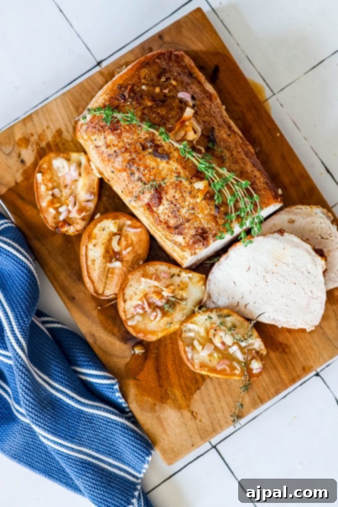 pork loin on a cutting board with roasted pears, shallots, and rosemary