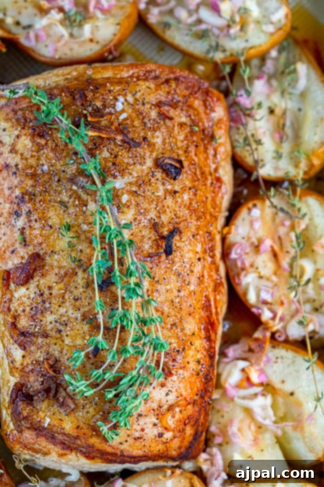 pork loin in a roasting dish with roasted pears, shallots, and rosemary