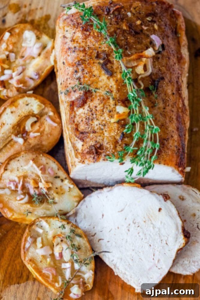 pork loin on a cutting board with roasted pears, shallots, and rosemary