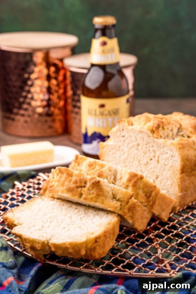 Freshly baked beer bread on a cooling rack in front of a bottle of beer, highlighting its golden crust and inviting texture.