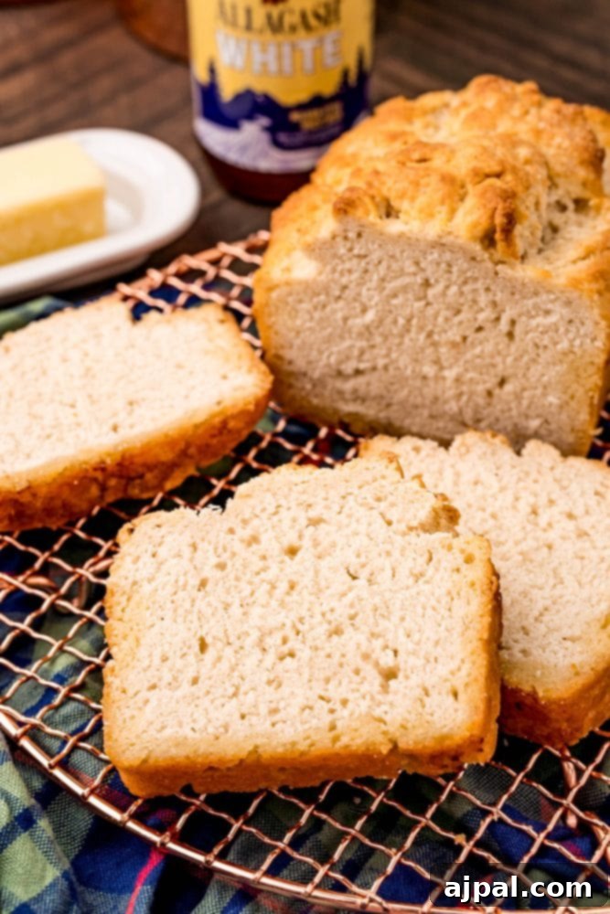 A freshly baked loaf of beer bread rests on a cooling rack, steam gently rising, showcasing its warm, inviting appearance.