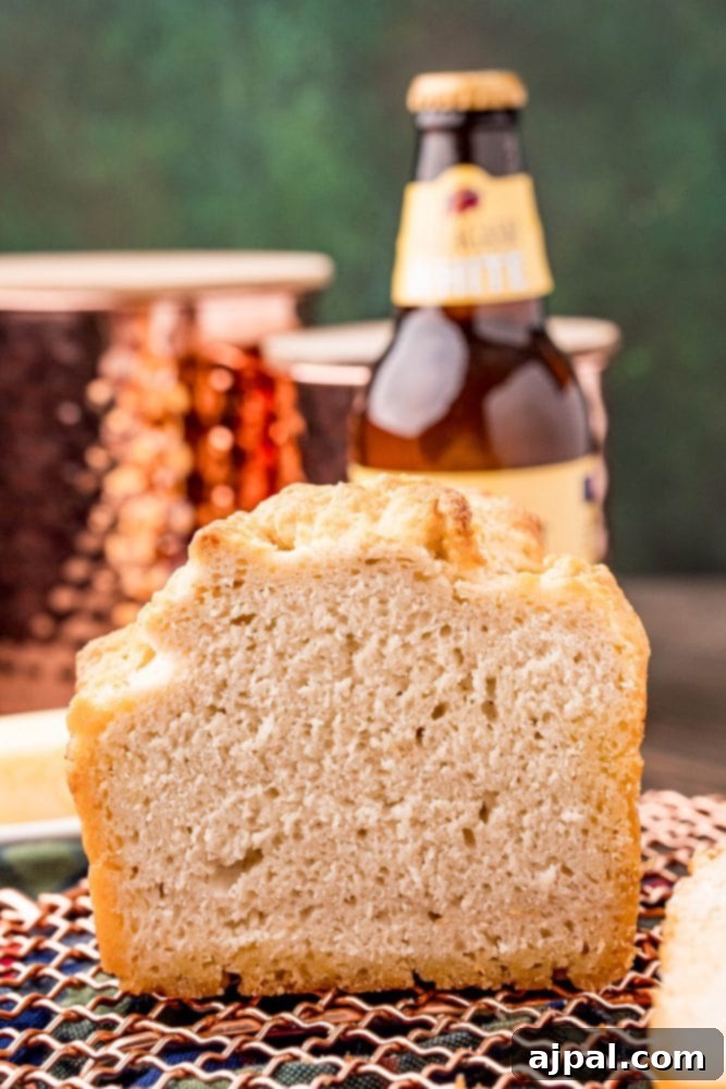 A slice of golden beer bread placed beside a bottle of beer, emphasizing its rustic charm and delicious appeal.