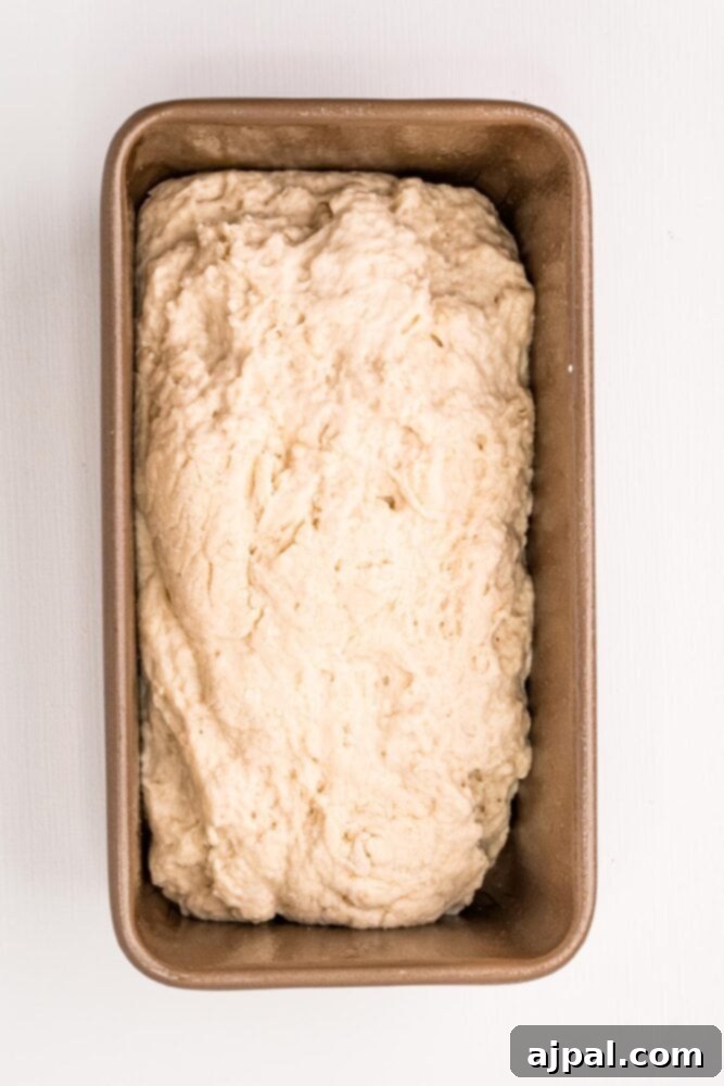 Beer bread dough neatly placed in a prepped nonstick loaf pan, ready for the oven.
