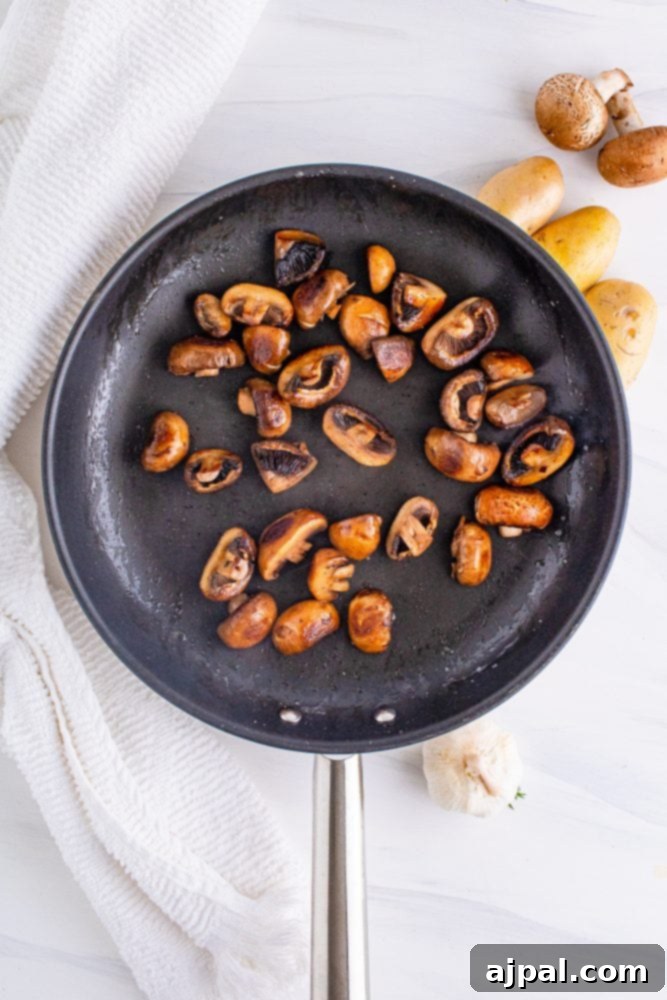 Sliced mushrooms browning in a pan, developing a rich, savory flavor and texture.