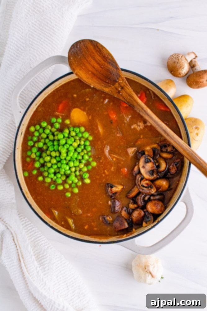 Green peas being gently added to the venison stew in a pot, preserving their vibrant color and fresh texture.