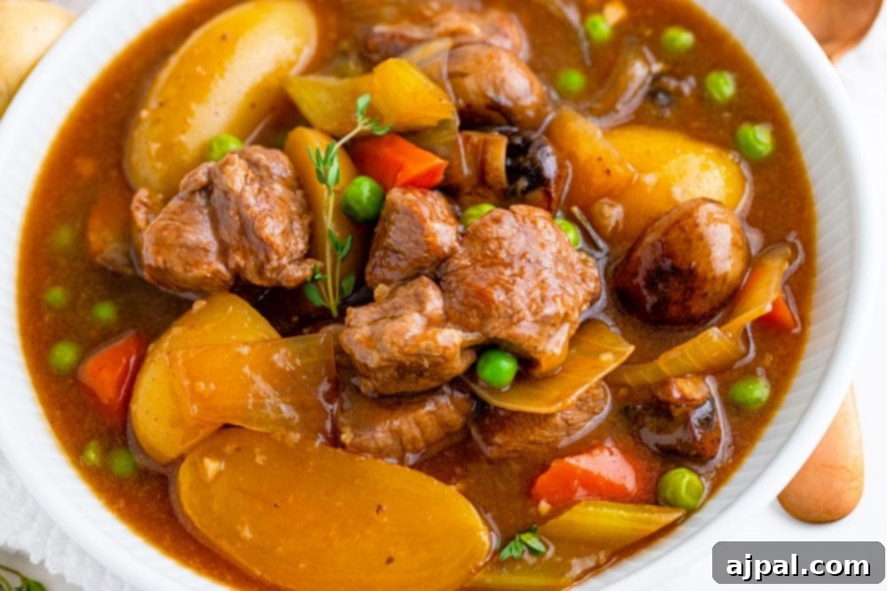 A close-up shot of venison stew in a Dutch oven with visible meat chunks, carrots, and peas, ready to be served.