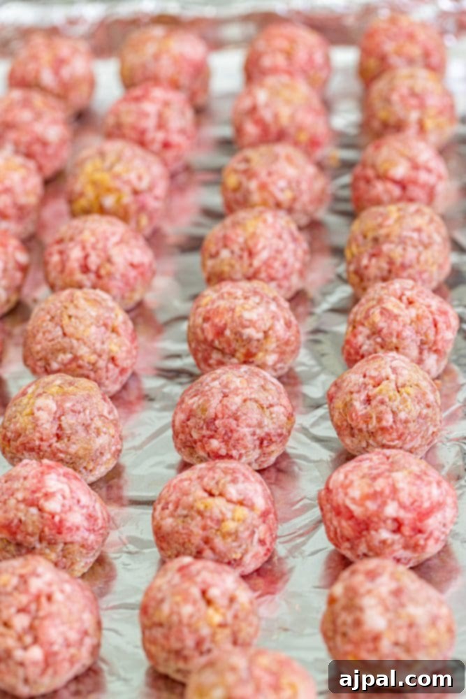 picture of meatballs being rolled on a lined baking sheet