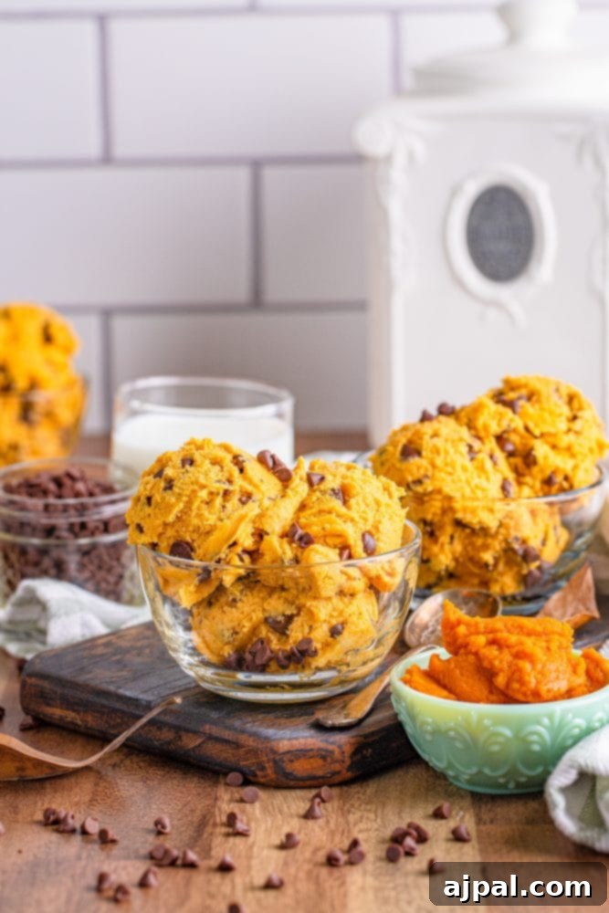 A close-up of a serving of edible pumpkin chocolate chip cookie dough on a rustic cutting board, highlighting its rich texture and chocolate chips.