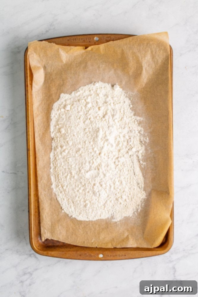 A baking sheet covered with flour, illustrating the first step of heat treating the flour for safe consumption.