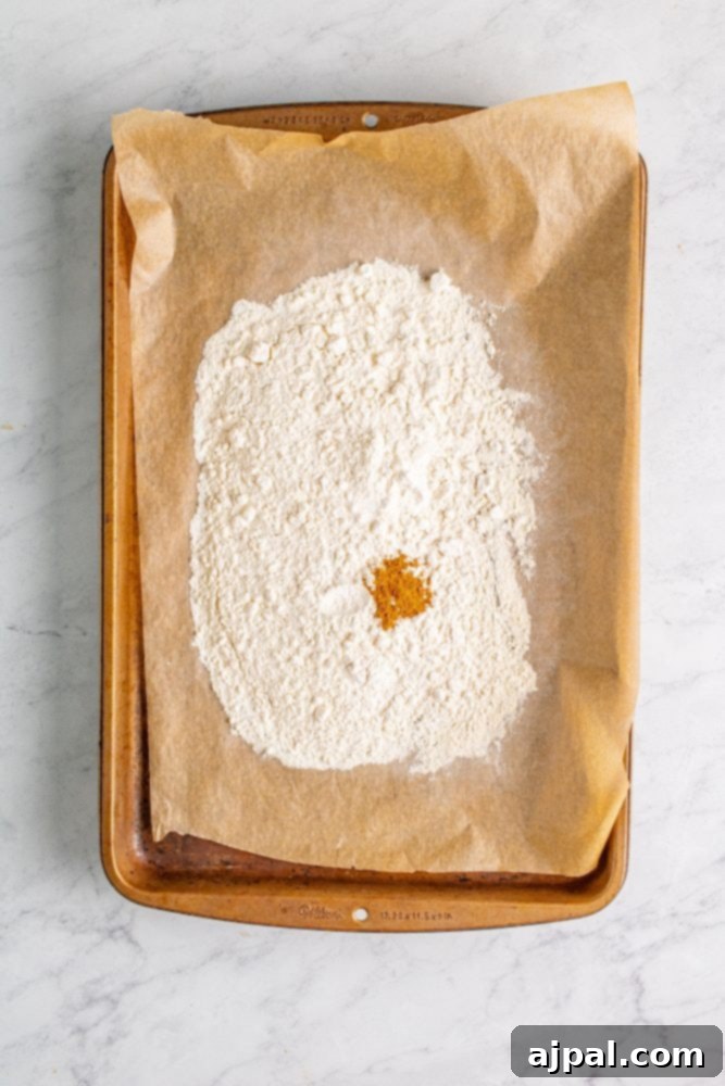 A baking sheet displaying flour sprinkled with cinnamon, indicating the integration of spices for the edible cookie dough.