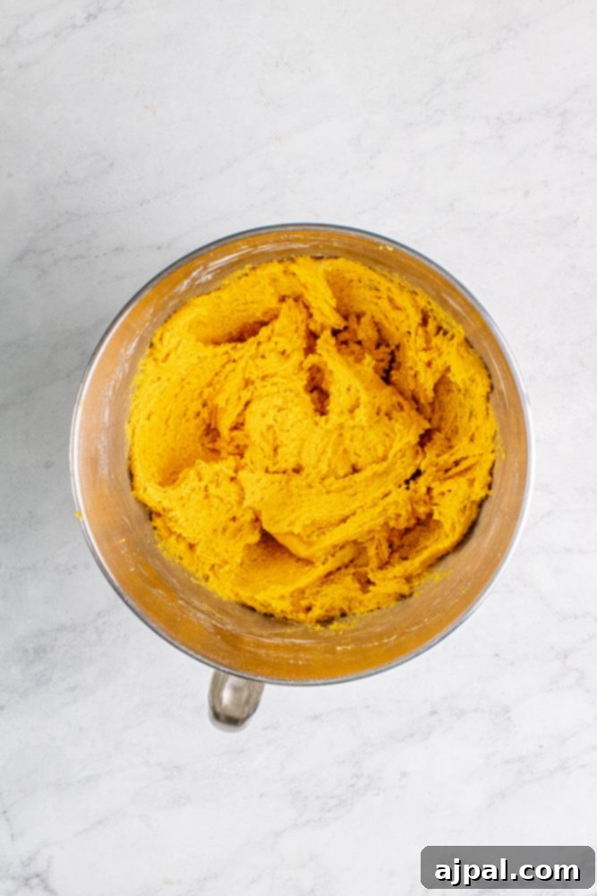 A bowl of pumpkin cookie dough, showing its rich orange hue before the final mix with chocolate chips.