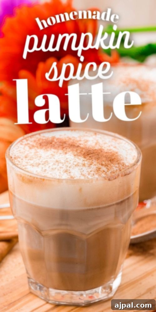 A tall glass of homemade pumpkin spice latte, adorned with whipped cream and a sprinkle of spice, standing on a light background.