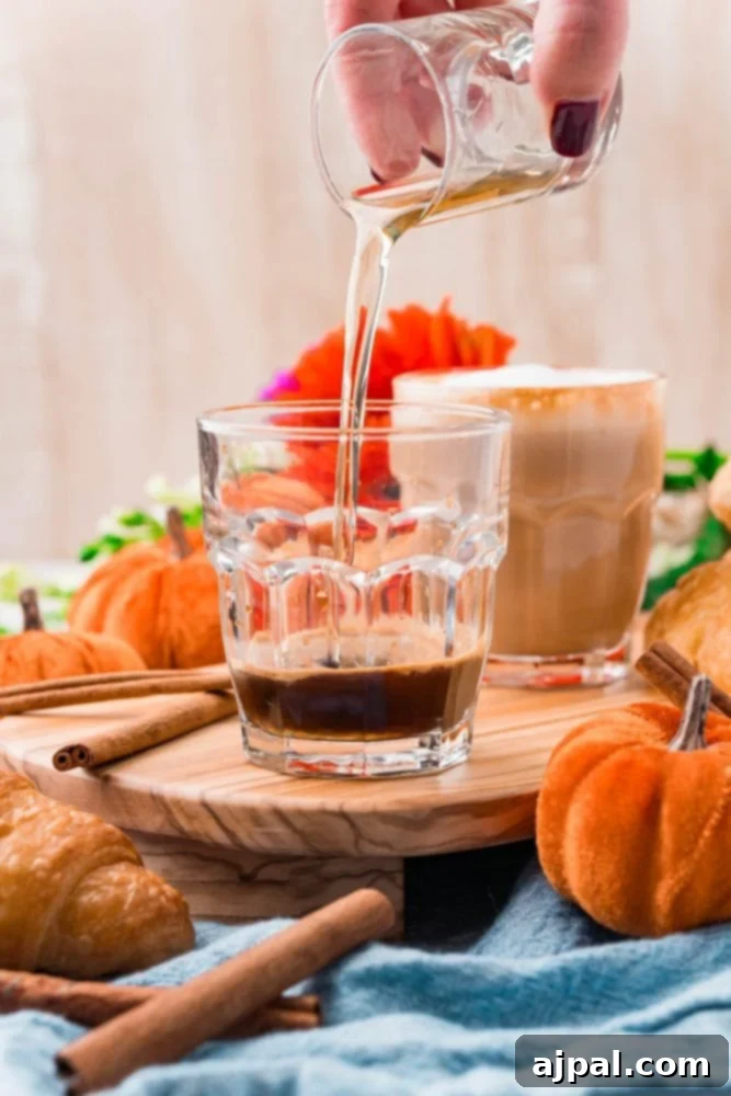 Assorted ingredients for pumpkin spice latte including cinnamon sticks, pumpkin pie spice, and espresso beans in a glass container.
