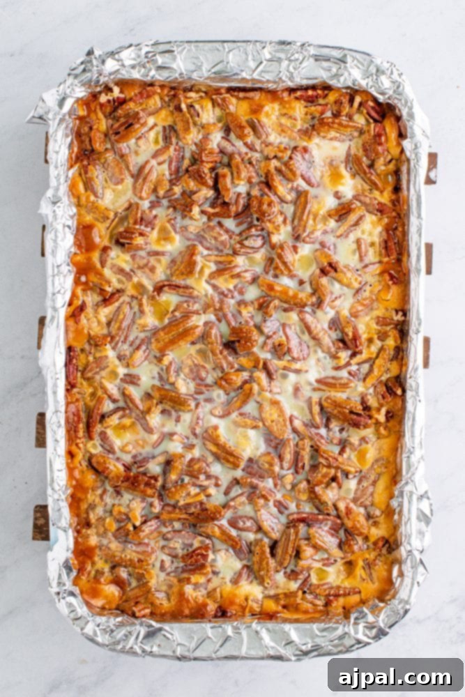 Warm pumpkin magic bars topped with toasted pecans and a sweet glaze, baked in a foil-lined sheet pan
