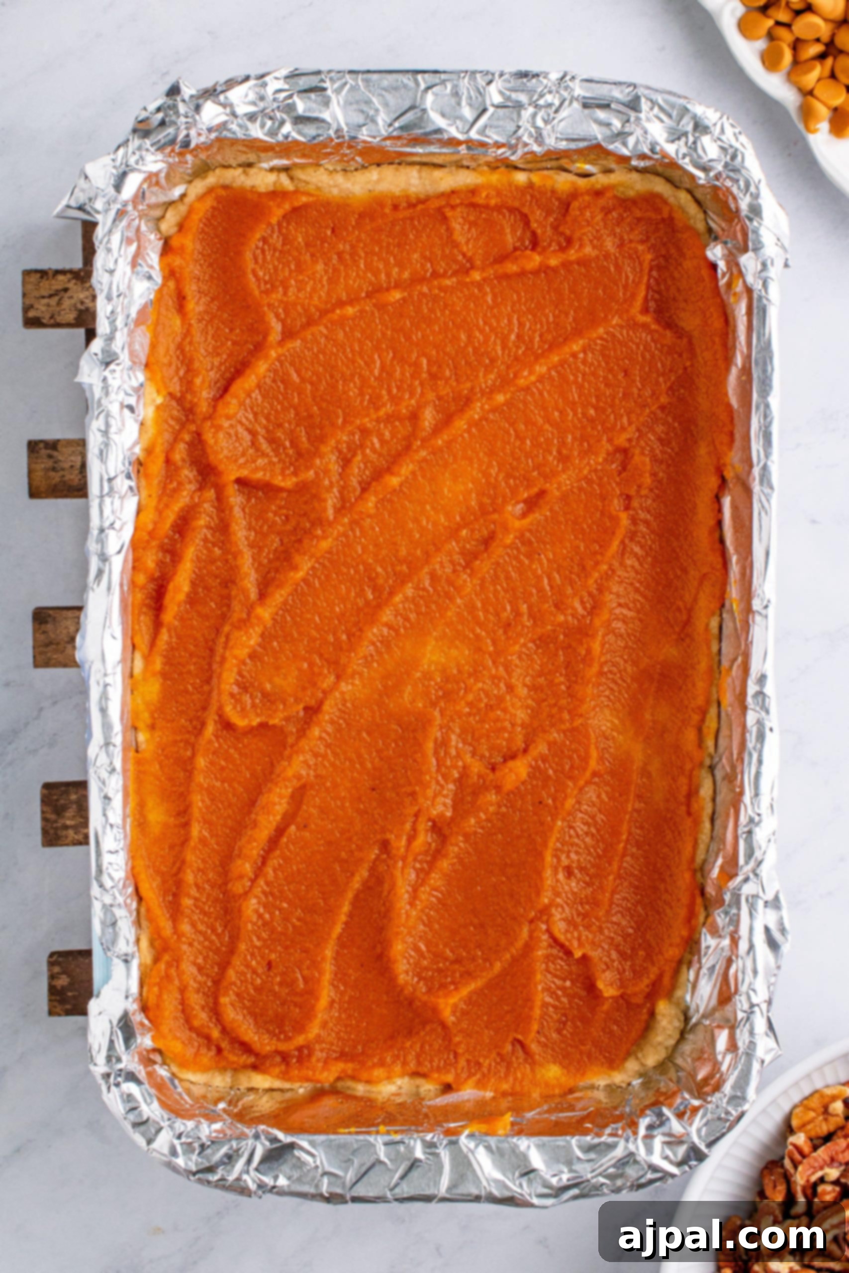 A casserole dish with a layer of sweet potato (or pumpkin) topped with a sparse scattering of nuts