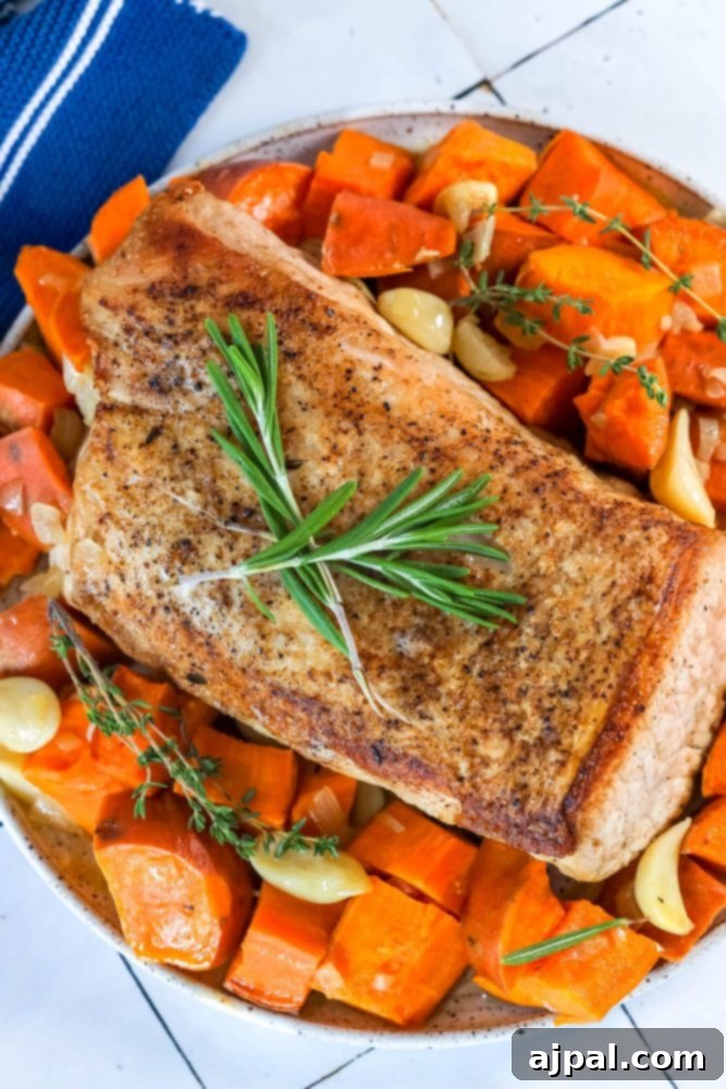 A vibrant, close-up shot of roasted pork loin slices and sweet potato chunks, garnished with fresh herbs, ready to be served as a delightful one-pot meal.