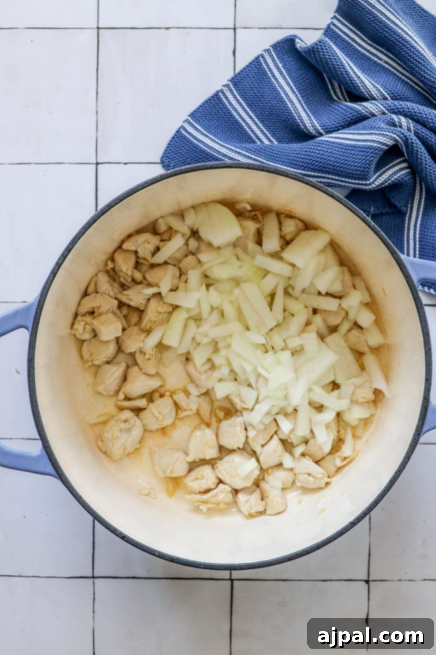 Diced chicken and onions sizzling and browning in a large, heavy-bottomed Dutch oven, forming the aromatic base of the soup.