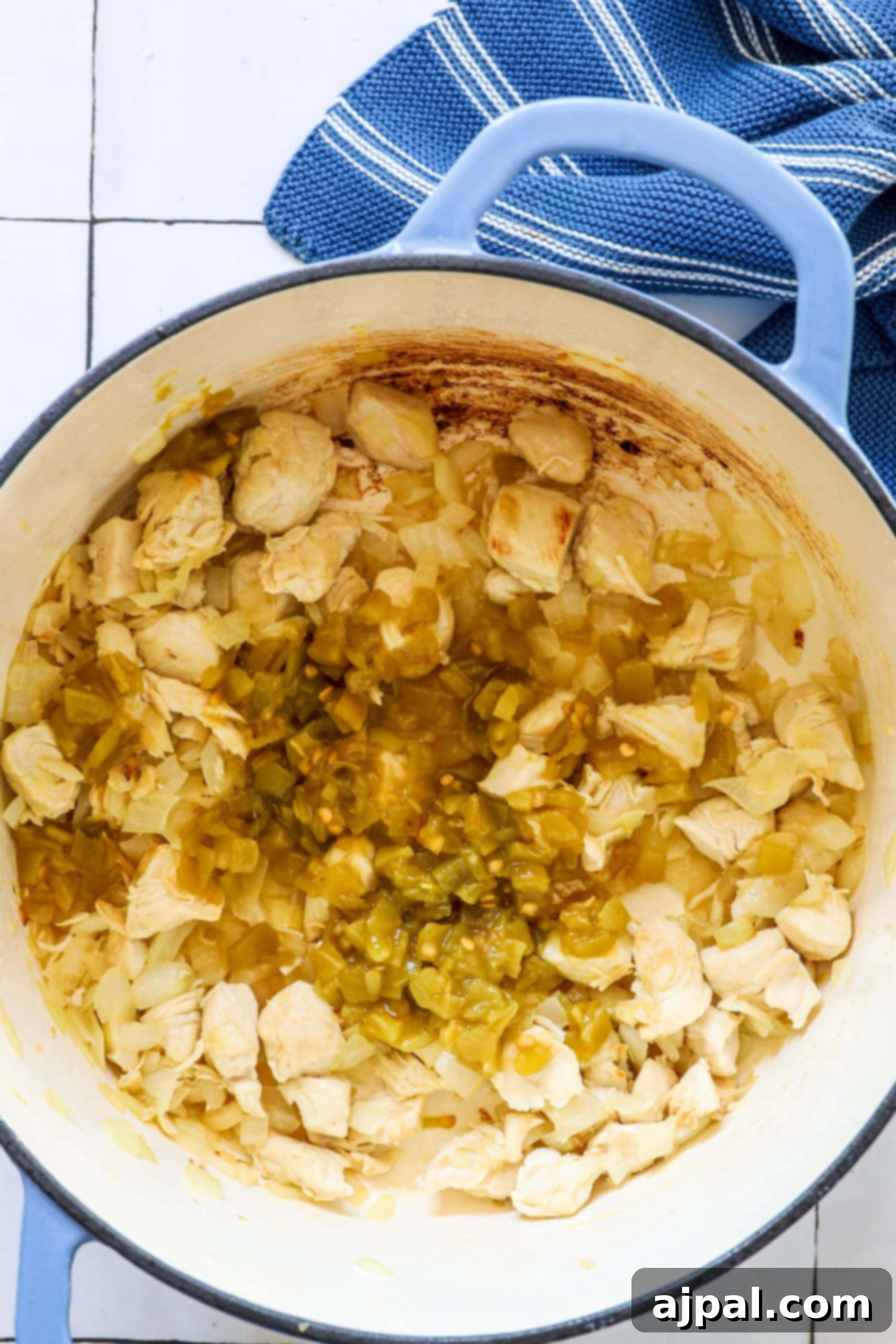 Sautéed diced chicken, green chilies, and browned onions infusing aromatic flavors in a Dutch oven, ready for the next additions.