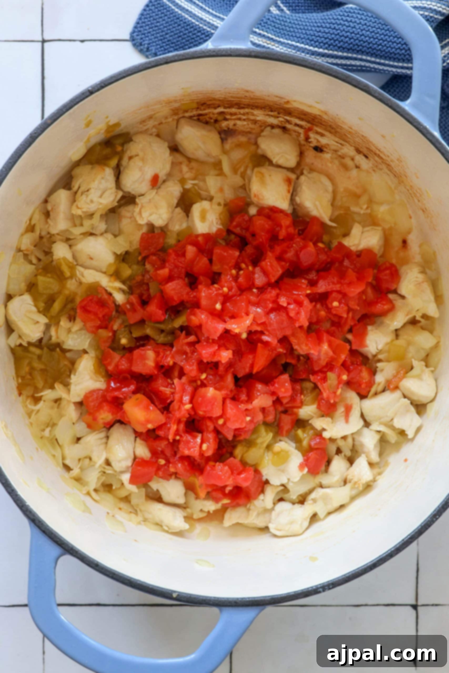 A rich mixture of browned chicken, Ro-tel tomatoes, and green chilies simmering in a Dutch oven, creating a robust base for the hearty soup.