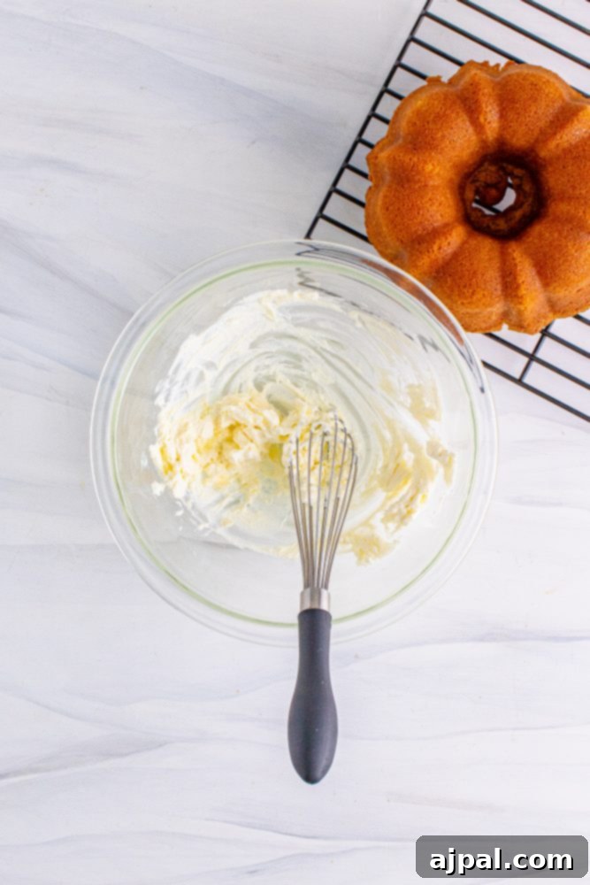 Perfect Air Fryer Pumpkin Bundt Cake 12 A whisk vigorously blending smooth, white icing in a small bowl, showcasing the creamy texture.