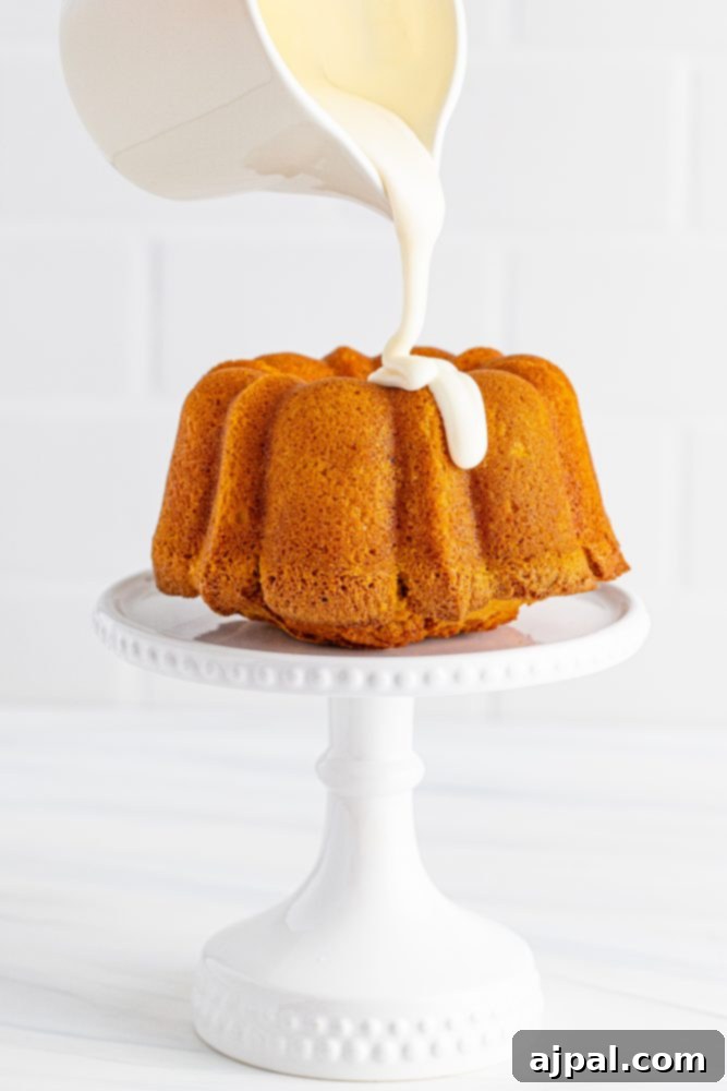 Perfect Air Fryer Pumpkin Bundt Cake 13 Smooth, white icing being generously poured over the top of a freshly baked bundt cake, creating a delicious cascade.