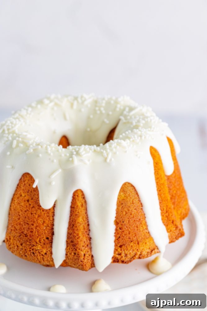 Perfect Air Fryer Pumpkin Bundt Cake 16 A stunning pumpkin bundt cake, generously coated with a smooth icing, presented on a white cake stand.