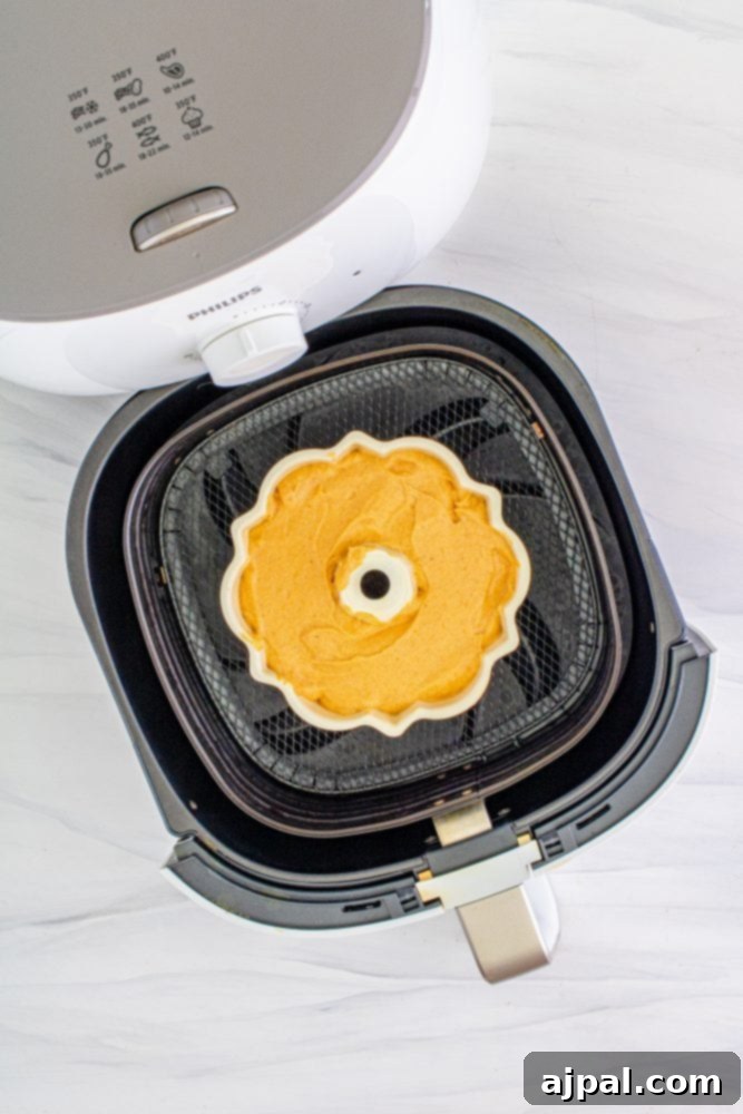 Perfect Air Fryer Pumpkin Bundt Cake 5 Pumpkin bundt cake batter carefully poured into a bundt pan, ready for the air fryer basket.