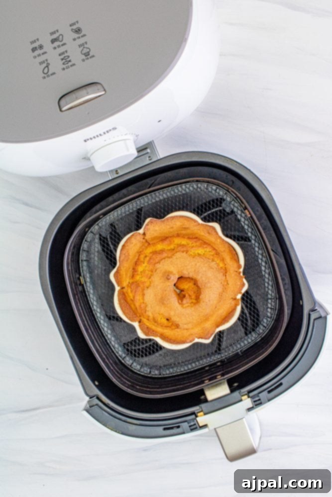 Perfect Air Fryer Pumpkin Bundt Cake 6 A freshly baked bundt cake resting in the air fryer basket after cooking, showcasing its perfect golden-brown exterior.