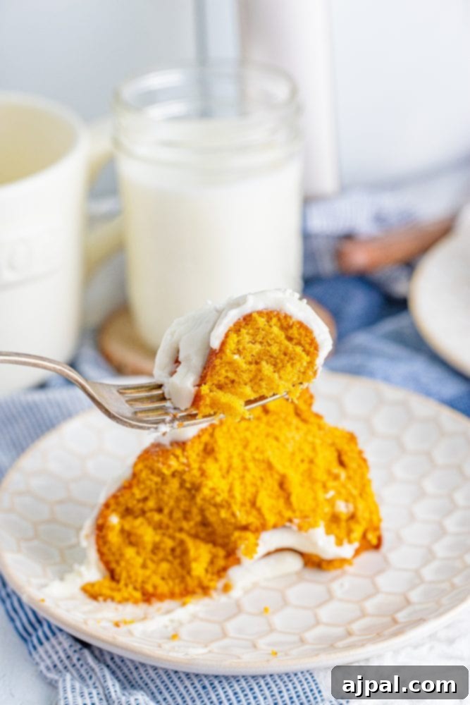 Perfect Air Fryer Pumpkin Bundt Cake 8 A delectable slice of air fryer pumpkin bundt cake, elegantly presented on a white plate with a fork, inviting you to take a bite.