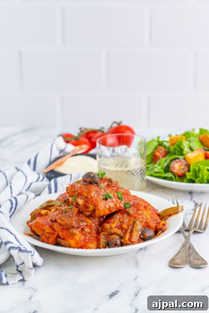 Simple Steps to Perfect Chicken Cacciatore 3 A vibrant plate of Chicken Cacciatore with a fresh green salad on a elegant marble table.