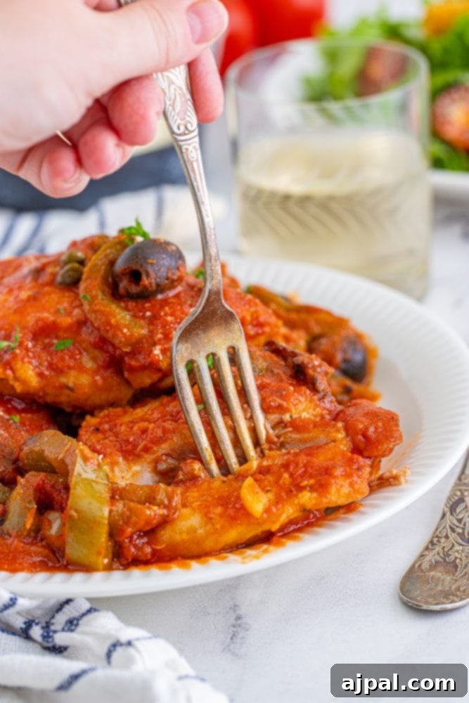 Simple Steps to Perfect Chicken Cacciatore 17 A person holding a fork over a delicious plate of Chicken Cacciatore, highlighting the appetizing texture.