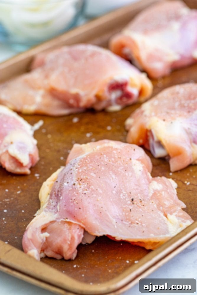 Simple Steps to Perfect Chicken Cacciatore 6 Seasoned raw chicken thighs ready for browning, laid out on a baking sheet.