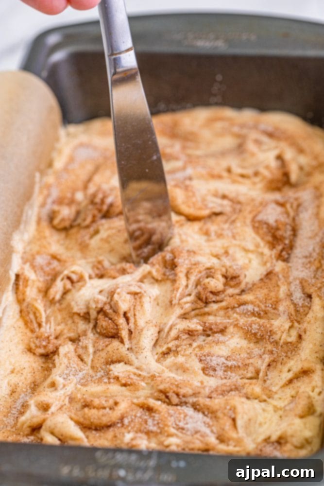picture of knife swirling cinnamon and sugar on top of bread dough with knife