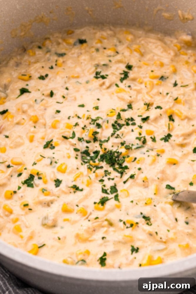 Creamy Corn Chowder 13 A large pan filled with creamy chicken and corn chowder, ready to be served, garnished with fresh herbs.