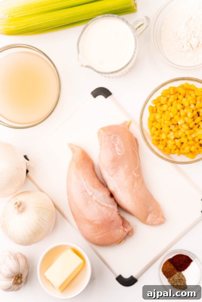 Creamy Corn Chowder 5 Ingredients for making chicken and corn chowder laid out on a cutting board, including chicken breasts and fresh corn.
